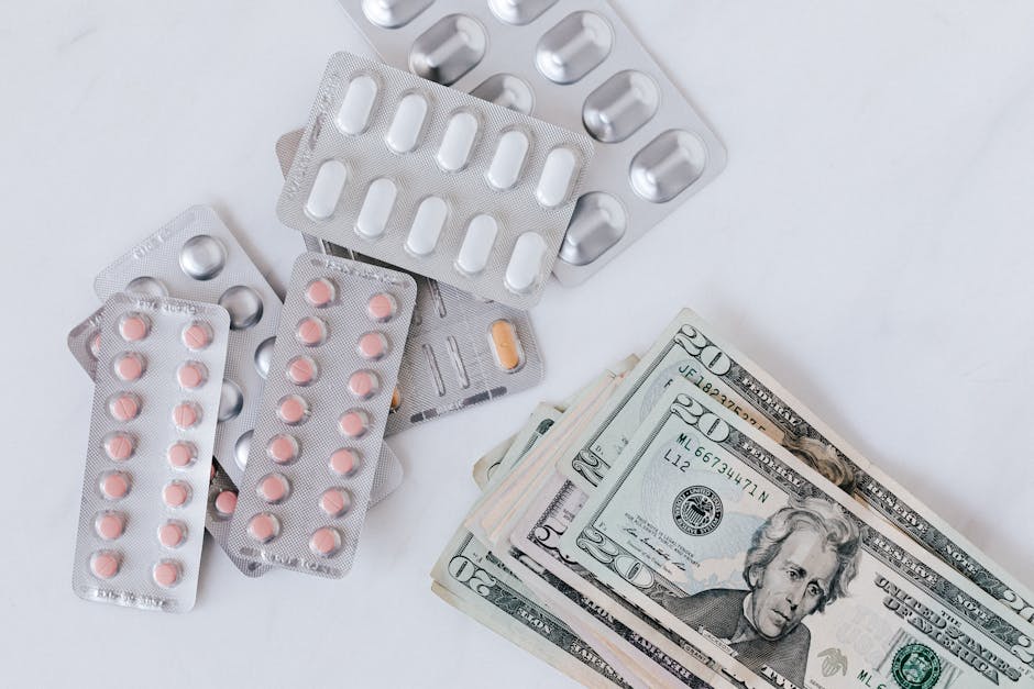 A collection of assorted blister packs containing pink and white pills and capsules, scattered on a white surface alongside folded twenty and fifty-dollar banknotes, with the pills and money appearing